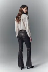 Pantalón jeanero de cuero ovino color marrón oscuro, de calce flare con efecto gastado y tachas aplicadas.