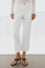 Jeans de tiro medio con corte flare y largo cropped. Presentan diseño de cinco bolsillos, trabillas en la cintura, raya planchada en el delantero y bajo desflecado. Cierre frontal con cremallera y botón.