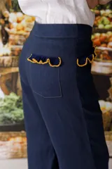 Pantalón de jean azul oscuro, de corte acampanado, con bolsillos delanteros con detalle de volados.