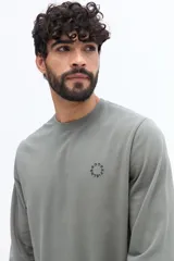 Remera de manga larga color negro, con escote redondo y un pequeño logo circular estampado en el pecho.