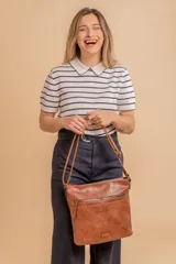 Cartera tipo bandolera de tamaño mediano confeccionada en símil cuero color marrón. Presenta una correa larga regulable, dos compartimientos principales y un bolsillo frontal con cierre de cremallera.