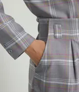 Short sastrero gris con estampado a cuadros blancos, amarillos y rosados. Tiene cintura media, pliegues, bolsillos y cierre frontal con cremallera.