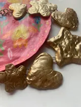 Collar dorado con cadena y dijes colgantes con formas de corazón, estrella y flor.
