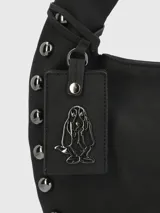 Cartera tipo hobo de cuero sintético color negro, con asa corta acolchada y tachas metálicas plateadas en el borde. Incluye llavero colgante con el logo de la marca.