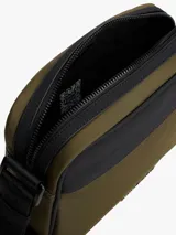 Bandolera Tommy Hilfiger color verde militar con detalles en negro y correa ajustable con la bandera de la marca. Incluye logo metálico en el frente y cierre de cremallera.