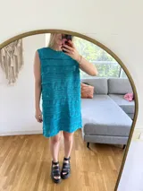 Vestido corto turquesa tejido en algodón con lurex, sin mangas y calado.
