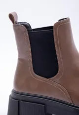 Bota marrón de caña media con elásticos laterales negros y suela track con plataforma.