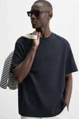 Camiseta negra relaxed fit confeccionada en tejido de algodón compacto con estructura piqué, cuello redondo y manga corta.