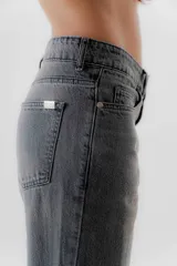 Pantalón jean de tiro medio color negro, corte mom, con bolsillos delanteros y traseros. Largo hasta el tobillo. Confeccionado en algodón 100%.