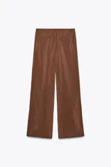 Pantalón marrón de tejido fluido, tiro medio, cintura elástica ajustable con cordones, bolsillos laterales y falsos bolsillos de vivo en la espalda.