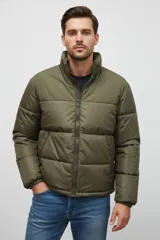 Campera acolchada color verde militar, con cuello alto y cierre frontal. Presenta un diseño de bloques horizontales de acolchado.
