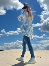 Camisa oversize celeste con rayas verticales blancas, de manga larga y cuello clásico.