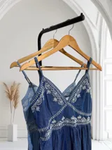 Vestido de jean azul con bordado floral blanco, breteles finos y corte midi.