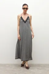 Vestido largo de tirantes finos, con escote en V decorado con encaje negro. El tejido presenta un estampado de cuadros vichy en blanco y negro.