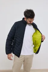 Campera capitoneada liviana color azul marino, con cuello alto y dos bolsillos exteriores con cierre. Interior del cuello a contratono.