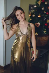 Vestido largo color marrón cobrizo con escote en V, cut outs laterales bajo el busto y breteles finos que se cruzan y atan en la espalda. Presenta un top con estampado abstracto en tonos marrones y dorados.