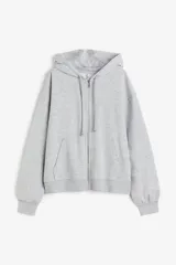Campera con capucha gris melange de felpa con interior cepillado suave, hombros caídos, capucha forrada en punto con cordón para ajustar, cierre frontal y bolsillo canguro. Puños y bajo en punto elástico acanalado.