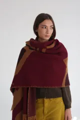 Ruana de lana con diseño abstracto en tonos beige, marrón y blanco. Presenta flecos en el borde inferior y capucha.