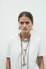 Set de tres collares de diferentes largos: gargantilla de anillas metálicas, collar largo de cuerda con charms metálicos y collar de eslabones metálicos con colgante de cuerno de resina.