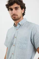 Camisa celeste de manga corta con cuello abotonado y bolsillo en el pecho.