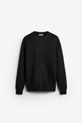 Sweater negro de punto perlado con cuello redondo y mangas largas con terminaciones en rib.
