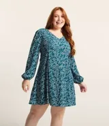 Vestido corto de crepé color verde azulado con estampado de mini corazones blancos, escote en pico, mangas largas con puños elásticos y cierre en la espalda.