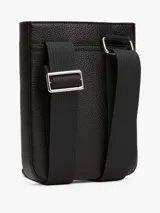 Bandolera negra de Tommy Hilfiger con acabado granulado, correa ajustable de tejido trenzado, bolsillo exterior abierto, cinta distintiva y logo metálico.