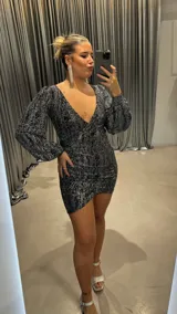 Minivestido de fiesta plateado con brillos, escote en V, mangas largas abullonadas y corte ajustado.