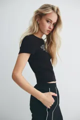 Remera negra entallada corta en punto acanalado de algodón con estampa frontal de pastelería francesa. Costuras planas para una comodidad óptima.