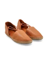 Alpargatas de cuero color marrón claro con suela de yute y tiras elásticas cruzadas en el empeine. Diseñadas en Uruguay y fabricadas en Turquía.