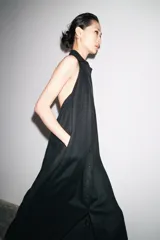 Vestido midi negro de lino, con cuello halter, hombros descubiertos, espalda descubierta, cierre frontal con botones y bajo asimétrico.