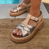 Sandalias bajas de cuero vacuno color beige con tiras cruzadas plateadas y hebilla lateral. Suela doble de goma deportiva con altura de 3cm adelante y 5,5cm atrás.