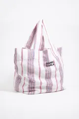 Bolso tipo shopper de lona color crudo con rayas verticales amarillas y grises. Tiene doble asa de hombro y logo de la marca estampado en el frente.