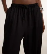 Pantalón femenino de corte fluido, color beige claro, con cintura elástica ajustable mediante un lazo.