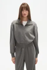 Campera gris de manga larga con cierre frontal, cuello alto y vivos blancos en los hombros y mangas.