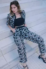 Conjunto de tres piezas con estampado floral blanco sobre fondo negro, compuesto por un top bandeau negro, una camisa de manga corta con cuello solapa y un pantalón largo de corte recto.