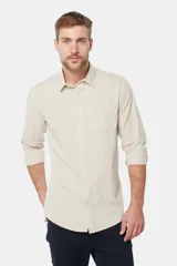 Camisa de lino color beige, de manga larga, con cuello clásico y bolsillo en el pecho.