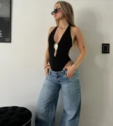 Body negro con escote halter, abertura en el pecho con detalle de aplique dorado y corte cavado.