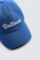Gorra azul con visera confeccionada en tejido de algodón y parche frontal con texto bordado en blanco. Ajuste en la parte posterior.