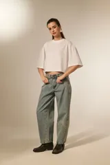 Remera blanca de manga 3/4, con cuello a la base y diseño holgado. Presenta un patrón de pequeños orificios y detalles de studs.