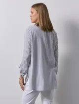 Blusa de gasa bambula a rayas verticales celestes y blancas, con cuello a la base, escote en v con botones y bordado negro. Mangas largas regulables con presilla y botón.