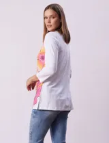 Blusa blanca de algodón con estampado de flores en tonos naranja y rosa, escote redondo con puntilla y mangas 3/4.