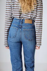 Jean de tiro alto y pierna recta, color azul medio. Confeccionado en 98% algodón y 2% elastano, con diseño clásico de cinco bolsillos.