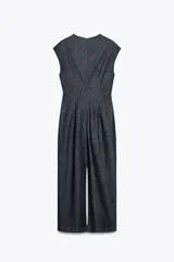 Vestido midi de denim azul oscuro, con cuello redondo y sisas. Presenta un aplique dorado en la cintura y abertura en la espalda. Cierre trasero con cremallera oculta.