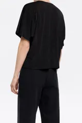 Camiseta negra fluida de corte boxy, con escote a la caja, manga corta y pliegues en el hombro.