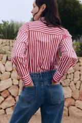 Pantalón de jean azul de corte recto, con tiro alto, cinco bolsillos y cierre con botones.