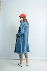 Tapado largo de jeans azul con bordado en la espalda, cuello camisero, bolsillos laterales y cierre frontal con botones.