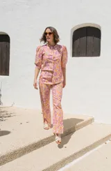 Camisa de lino estampada con flores en tonos rosa y naranja, con cuello mao, mangas cortas abullonadas y cierre frontal con botones.