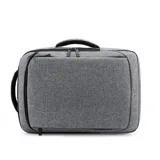 Mochila gris con doble bolsillo frontal con cierre, compartimento acolchado para laptop, puerto USB externo, asa de mano y faja trasera para acoplar a la manija de la valija.