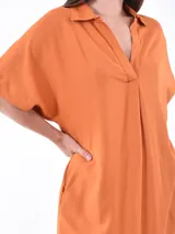 Vestido largo color naranja, de corte amplio, con cuello camisero y mangas cortas.
